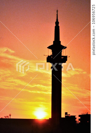 Mina red call tower of the mosque (chapel) reflected in the setting sun) Mina red call tower of the mosque (chapel) reflected in the setting sun) 106956725