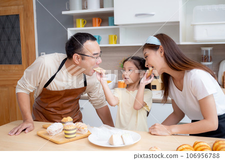 Happy family with father, mother and daughter in kitchen eating sandwich for healthy together. 106956788