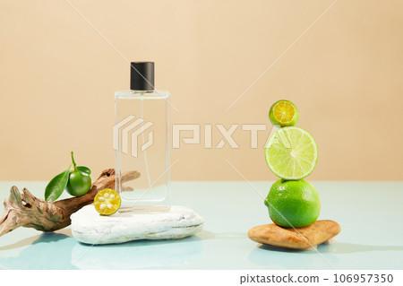 A stack of kumquats and limes displayed with a perfume bottle standing on a block of stone. Lime and Kumquat have the antioxidants that strengthen collagen 106957350