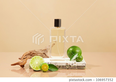 Spray bottle containing liquid placed on stone podium with kumquats and limes. The scent of Lime and Kumquat essential oil creates a feeling of comfort 106957352