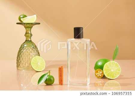 Transparent bottle without label arranged with a half of cinnamon, kumquat and lime cut in slices. Lime and Kumquat improve your health or maintain your weight 106957355