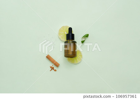 Round slices of lime placed under a dropper bottle. Cinnamon with lime peel displayed on the background. Concept of organic fruit that good for health 106957361