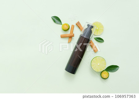 Few cinnamon sticks, slices of lime and kumquat arranged on light background with unbranded bottle. Copy space. Lime and Kumquat are rich in vitamin C and antioxidants 106957363