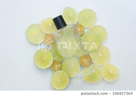 Kumquat and lime cut in round slices arranged under a transparent bottle. Mockup design. Lime and Kumquat are often used to accent flavors in foods 106957364