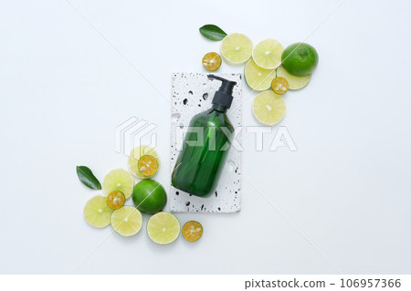 Rectangle stone podium with a cosmetic pump bottle placed on. Many slices of lime and kumquat featured. Lime and Kumquat can provide 32 percent of the vitamin C needed in a day 106957366