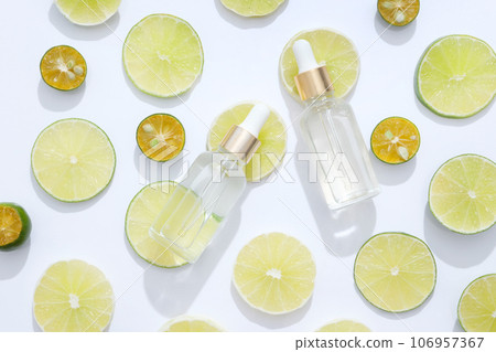 Lime and kumquat in round slices decorated on white background with glass dropper bottles. Lime and Kumquat are the ingredient to product cosmetic serum Lime and kumquat in round slices decorated on white background with glass dropper bottles. Lime and Kumquat are the ingredient to product cosmetic serum 106957367