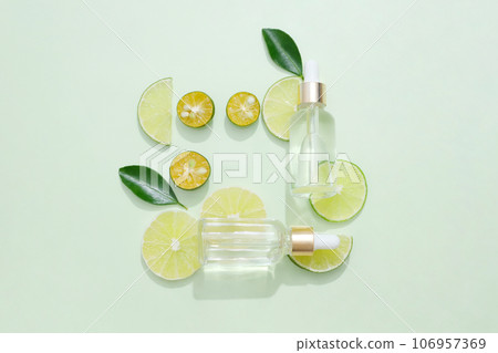 Serum bottles without label arranged with green leaves and several slices of kumquat and lime. Natural cosmetic concept. Empty label for branding mockup 106957369