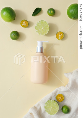 Flat lay of blank label pump bottle decorated with kumquat and lime on white towel. Lime and Kumquat help keep kidney stones at bay. Organic fruit concept 106957375
