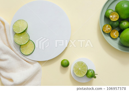 Light background featured podiums in round-shaped, white towel and a dish of kumquat and lime. Vacant space for beauty product advertising of Lime and Kumquat extract Light background featured podiums in round-shaped, white towel and a dish of kumquat and lime. Vacant space for beauty product advertising of Lime and Kumquat extract 106957378