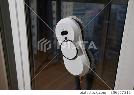 A window cleaner robot washes glass against the backdrop of multi-storey buildings. 106957811
