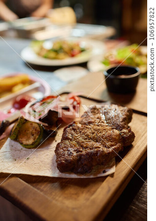 steak served on a wooden tray with grilled vegetables. 106957822