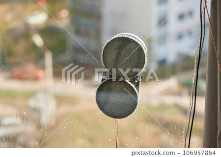 A window cleaner robot washes glass against the backdrop of multi-storey buildings. 106957864