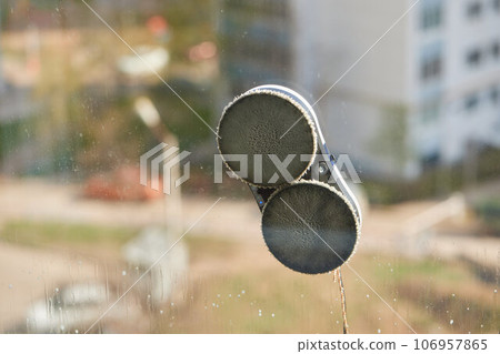 A window cleaner robot washes glass against the backdrop of multi-storey buildings. 106957865