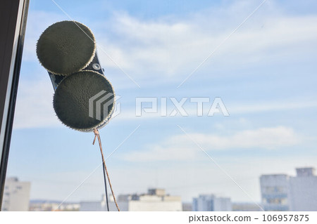 A window cleaner robot washes glass against the backdrop of multi-storey buildings. 106957875