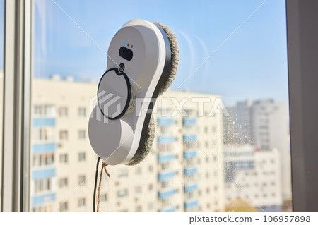 A window cleaner robot washes glass against the backdrop of multi-storey buildings. 106957898