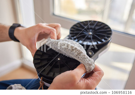 A window cleaner robot washes glass against the backdrop of multi-storey buildings. 106958116