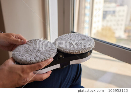 A window cleaner robot washes glass against the backdrop of multi-storey buildings. 106958123