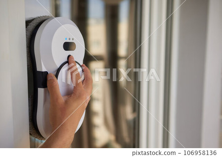 A window cleaner robot washes glass against the backdrop of multi-storey buildings. A window cleaner robot washes glass against the backdrop of multi-storey buildings. 106958136