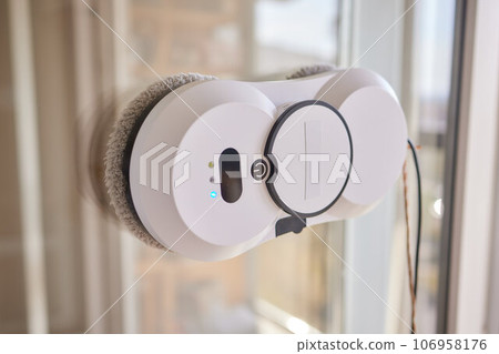 A window cleaner robot washes glass against the backdrop of multi-storey buildings. A window cleaner robot washes glass against the backdrop of multi-storey buildings. 106958176