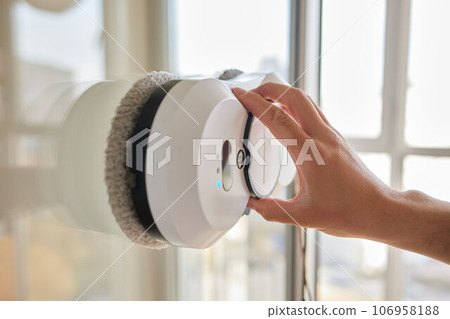 A window cleaner robot washes glass against the backdrop of multi-storey buildings. 106958188