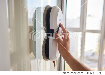 A window cleaner robot washes glass against the backdrop of multi-storey buildings. 106958190