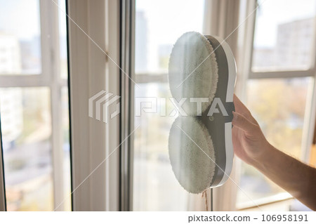 A window cleaner robot washes glass against the backdrop of multi-storey buildings. 106958191