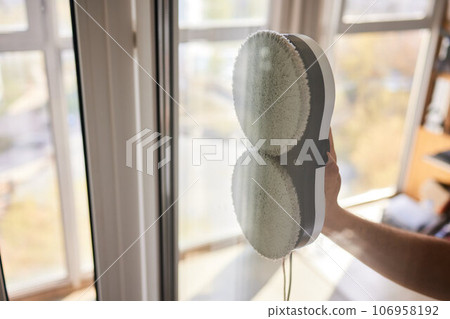 A window cleaner robot washes glass against the backdrop of multi-storey buildings. 106958192