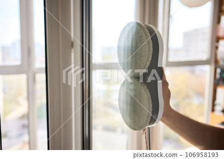 A window cleaner robot washes glass against the backdrop of multi-storey buildings. 106958193