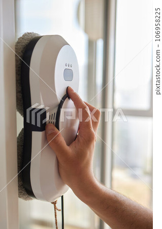 A window cleaner robot washes glass against the backdrop of multi-storey buildings. 106958225