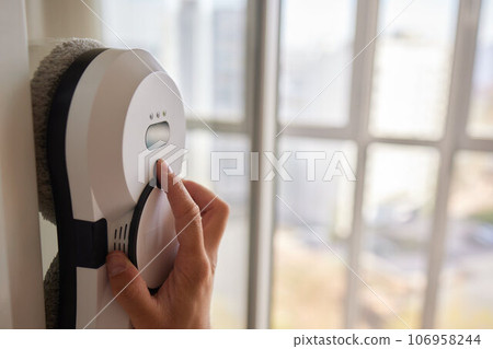 A window cleaner robot washes glass against the backdrop of multi-storey buildings. 106958244