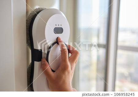 A window cleaner robot washes glass against the backdrop of multi-storey buildings. 106958245