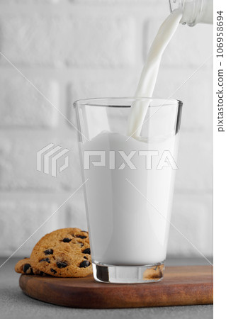 milk pouring in glass from bottle and chocolate chip cookies near milk pouring in glass from bottle and chocolate chip cookies near 106958694