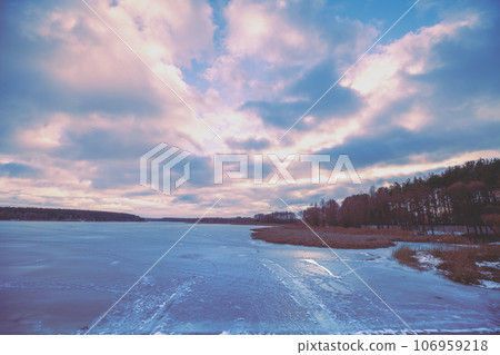 Dramatic winter sunset over the frozen lake. Serene lake in the evening. Nature landscape 106959218