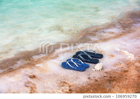 Beach scene Dead sea shore. Female and male flip flop sandals on the beach Beach scene Dead sea shore. Female and male flip flop sandals on the beach 106959270