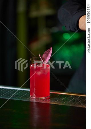 Barman in shirt and apron making an alcoholic drink with ice in a cocktail glass. 106959384
