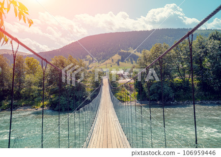 Wooden suspension bridge over a mountain river Wooden suspension bridge over a mountain river 106959446