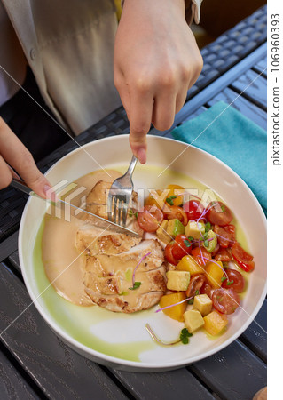 Young woman hand eating donburi with chicken and rice using knife and fork fom bowl. 106960393