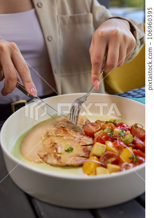Young woman hand eating donburi with chicken and rice using knife and fork fom bowl. 106960395