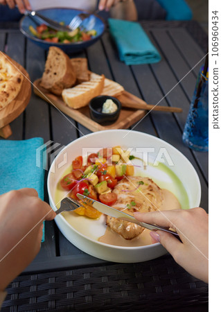 Young woman hand eating donburi with chicken and rice using knife and fork fom bowl. Young woman hand eating donburi with chicken and rice using knife and fork fom bowl. 106960434