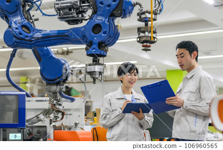 Engineers talking in a room with manufacturing machines 106960565