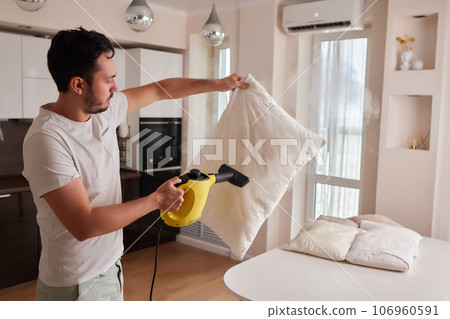 Using dry steam cleaner to sanitize pillow. 106960591