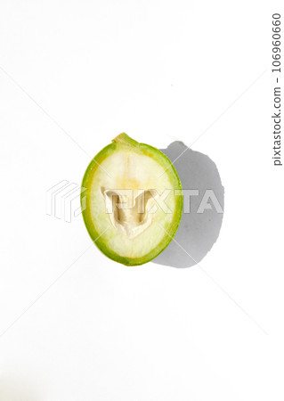 The green outer shells of the unripe walnuts are cut in half, green walnuts 106960660