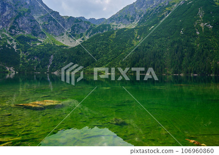 Amazing view on mountains range near beautiful lake at summer day. Tatra National Park in Poland. Panoramic view on Morskie Oko or Sea Eye lake in Five lakes valley 106960860