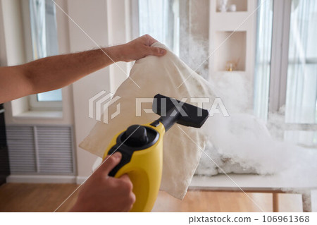 Using dry steam cleaner to sanitize pillow. 106961368
