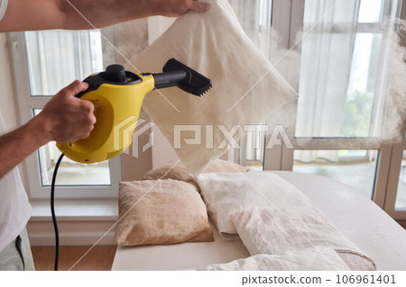 Using dry steam cleaner to sanitize pillow. Using dry steam cleaner to sanitize pillow. 106961401
