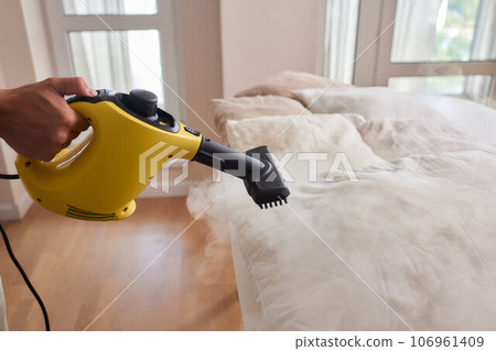 Using dry steam cleaner to sanitize pillow. 106961409