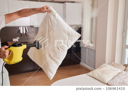Using dry steam cleaner to sanitize pillow. 106961410