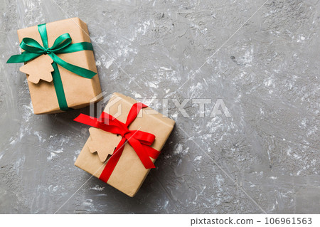 wrapped christmas or other holiday handmade present in paper with colored ribbon. Present box, decoration of gift on colourfull table, top view with copy space 106961563