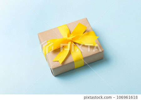Wrapped christmas or other holiday handmade present in craft paper with colored ribbon. Present box, decoration of gift on table, top view with copy space Wrapped christmas or other holiday handmade present in craft paper with colored ribbon. Present box, decoration of gift on table, top view with copy space 106961618