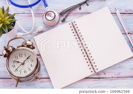 Flat lay photo with blank notebook, pen and alarm clock with flower on wooden table background. 106962566
